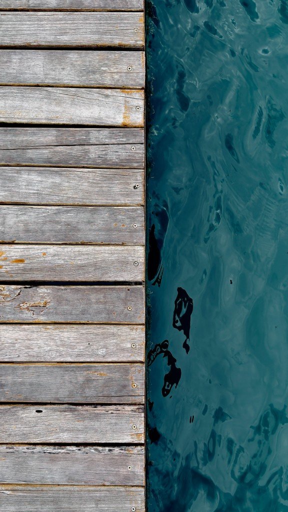 wooden pier next to teal water